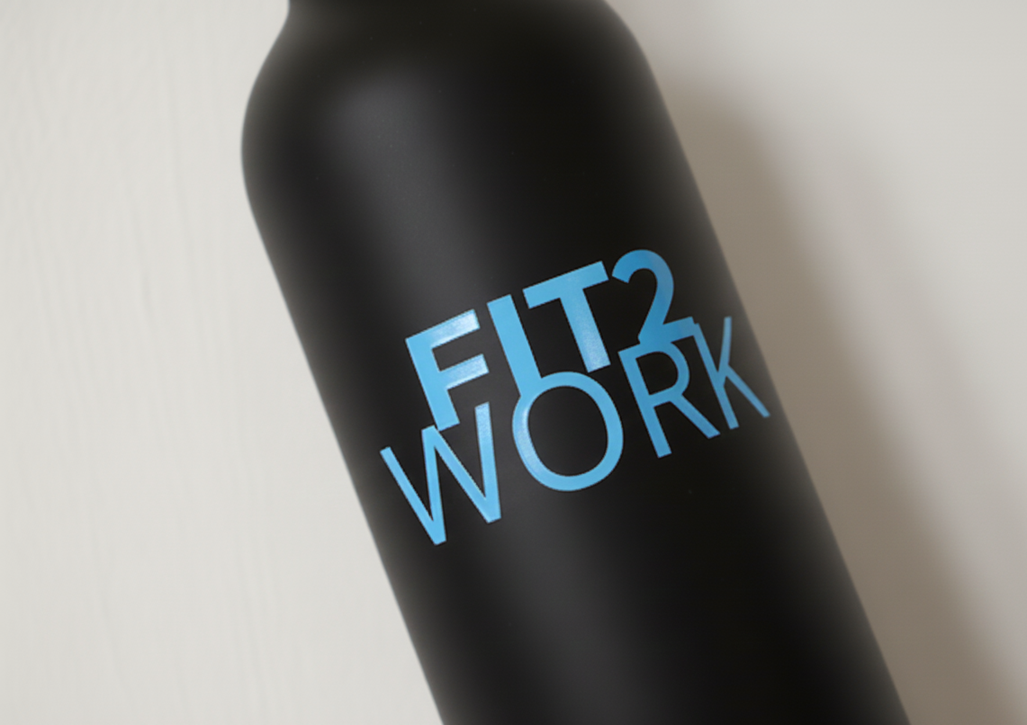 Logótipo FIT2WORK aplicado numa garrafa através da tecnologia Estampagem DTF UV. A solução ideal para personalizar materiais rígidos e não convencionais, garantindo alta resistência e um toque moderno.